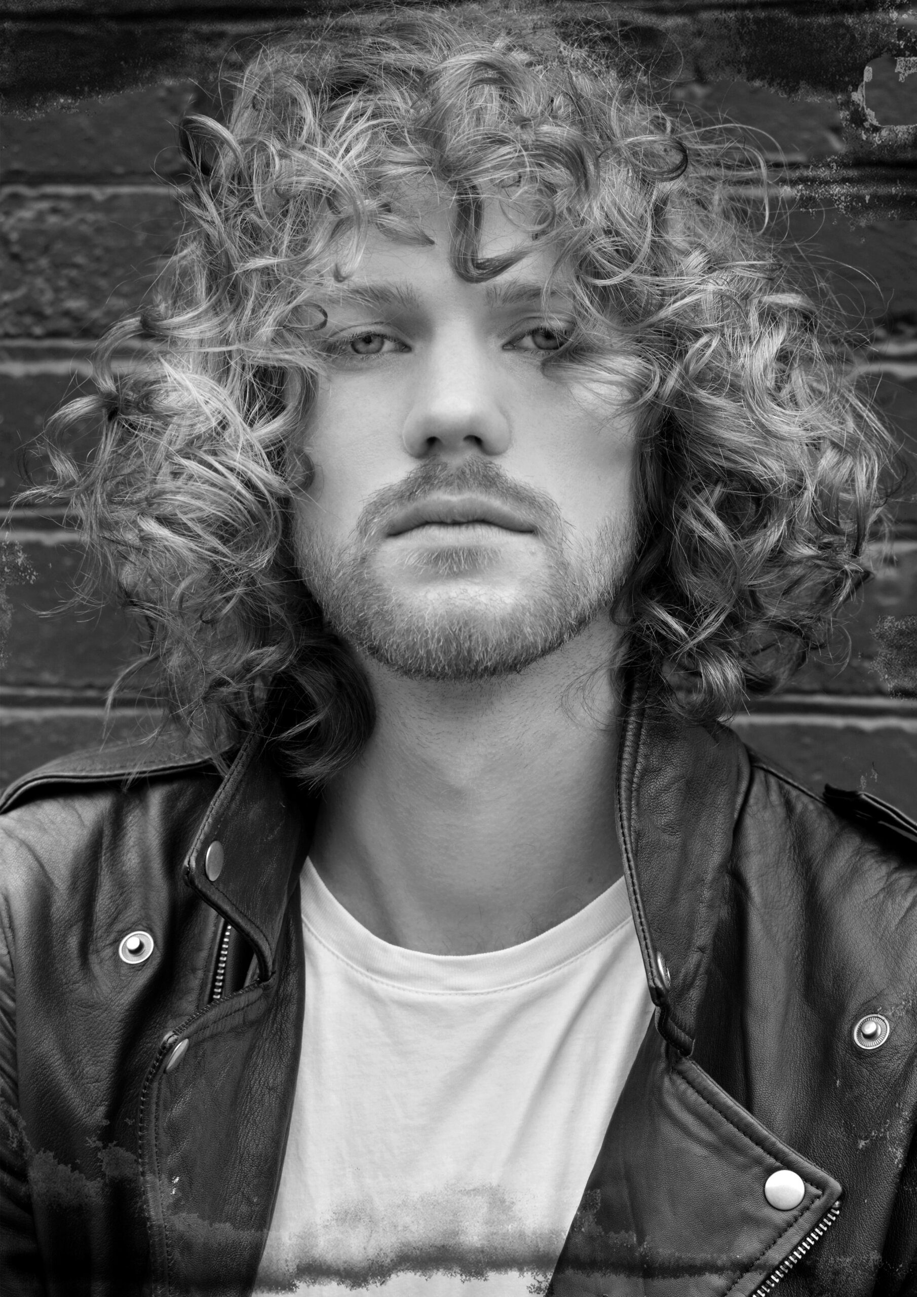 Men’s curly haircut with short sides and defined texture on top