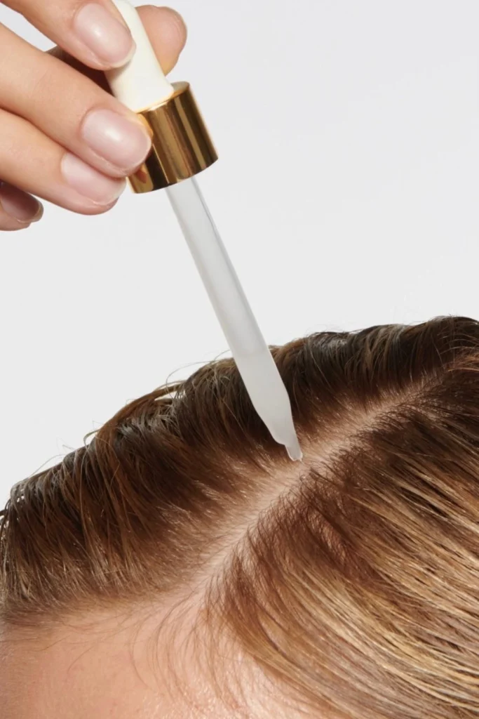 close up of applying dropper to the scalp of blonde hair