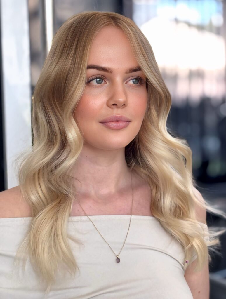 Glossy blonde hair result with soft waves and bright salon shine