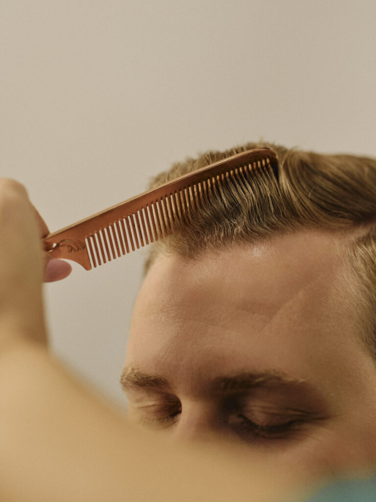Epic stylist combing short blonde men’s hair during a colour appointment