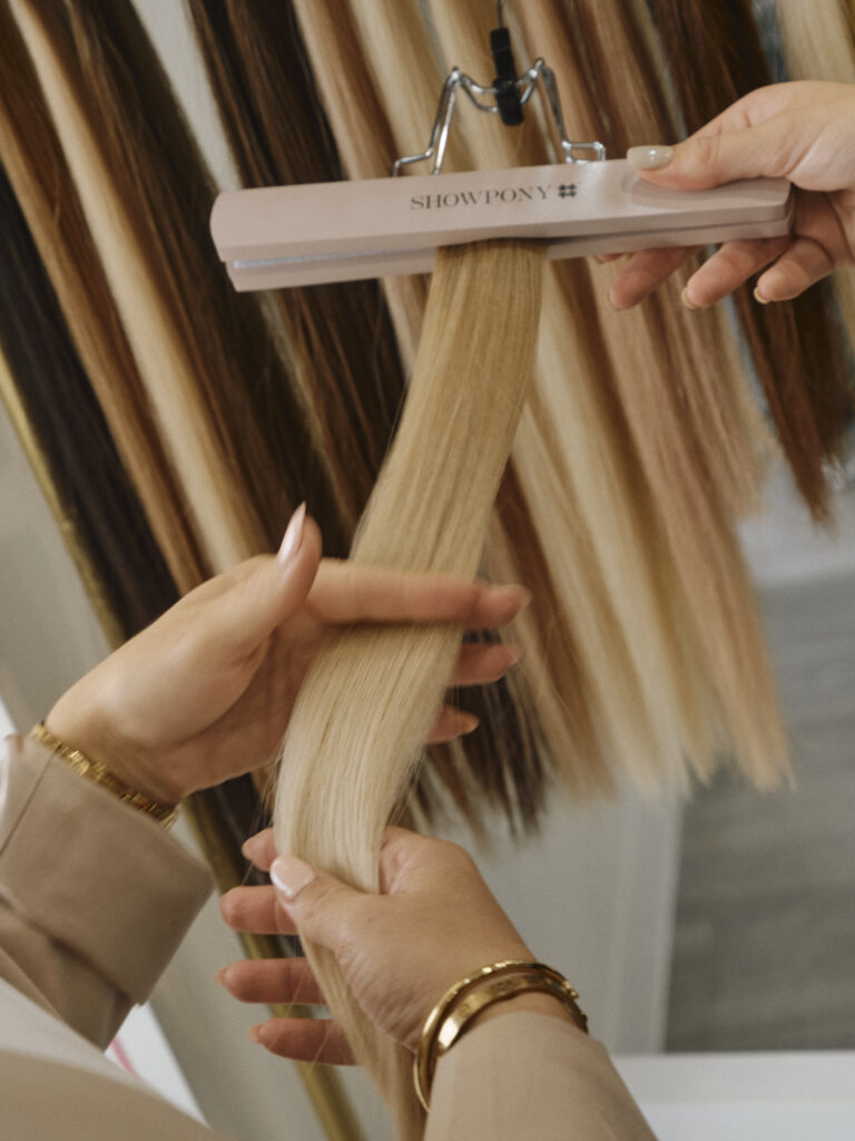 Epic stylist holding blonde Showpony tape hair extensions during colour selection