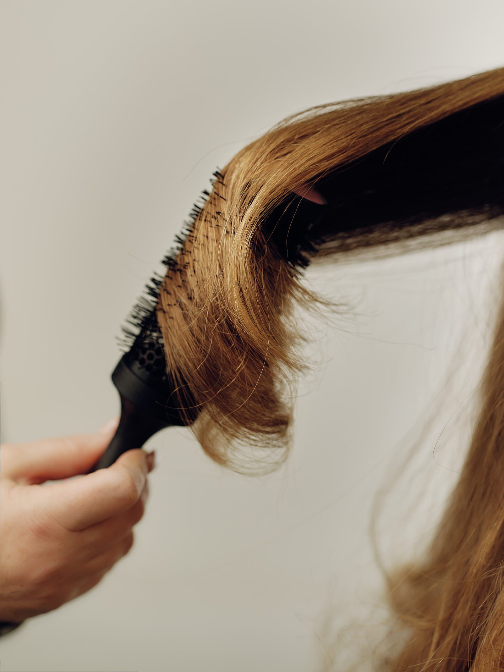 Epic Hair Designs stylist creating a smooth blonde blow-dry with a round brush