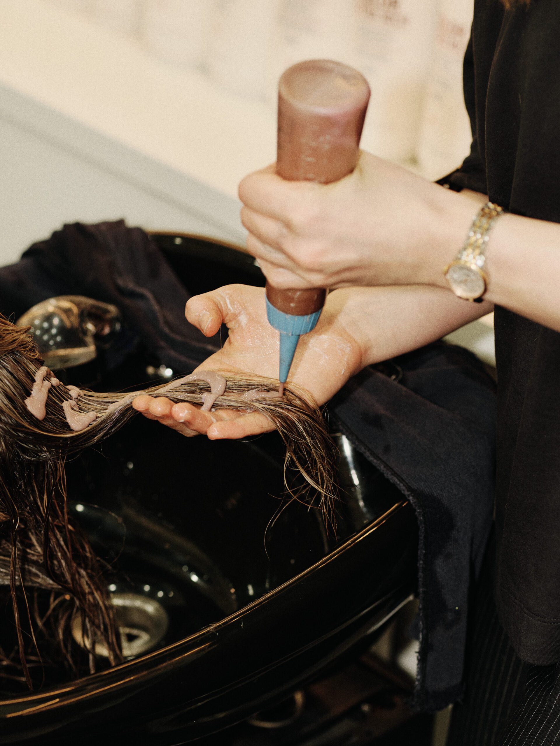 Epic Hair Designs stylist applying a conditioning treatment to a client’s hair at the basin