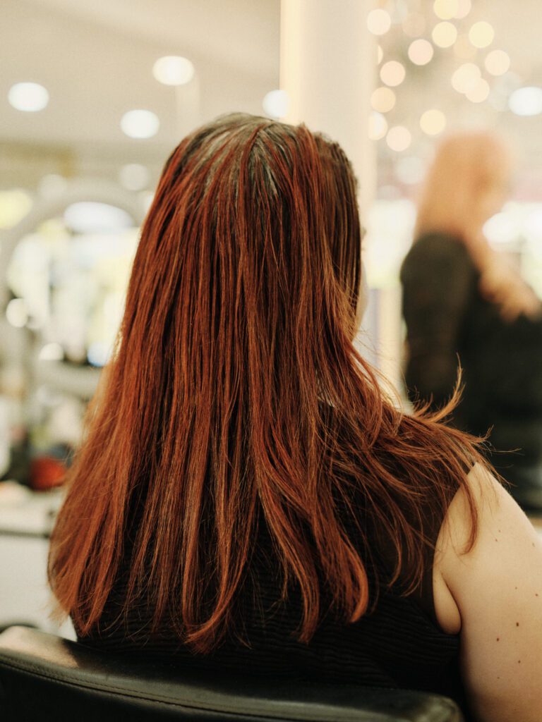 Back view of long auburn hair with a strong layered perimeter at Epic