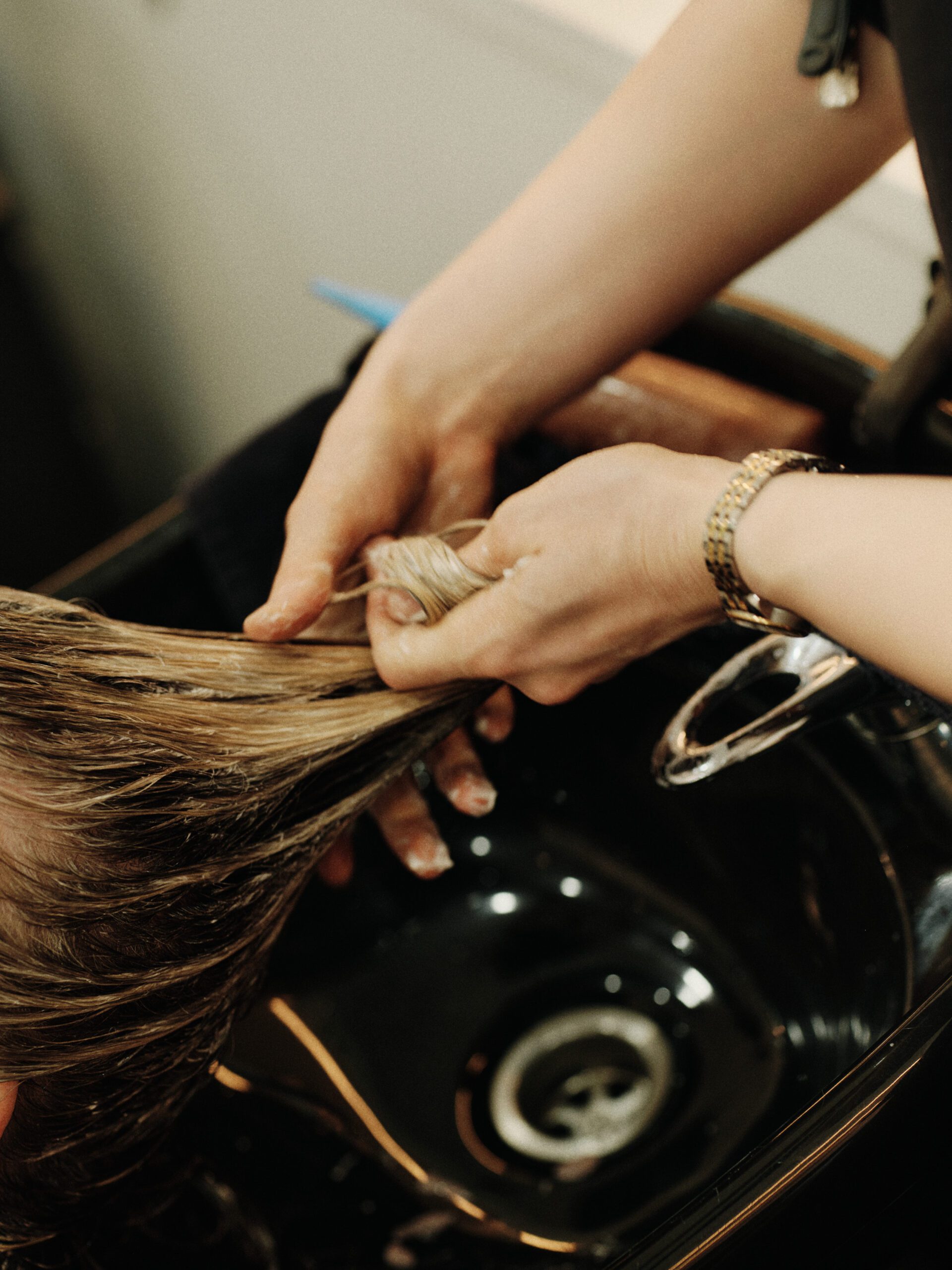 Professional salon treatment being rinsed from a client's hair at Epic Hair Designs