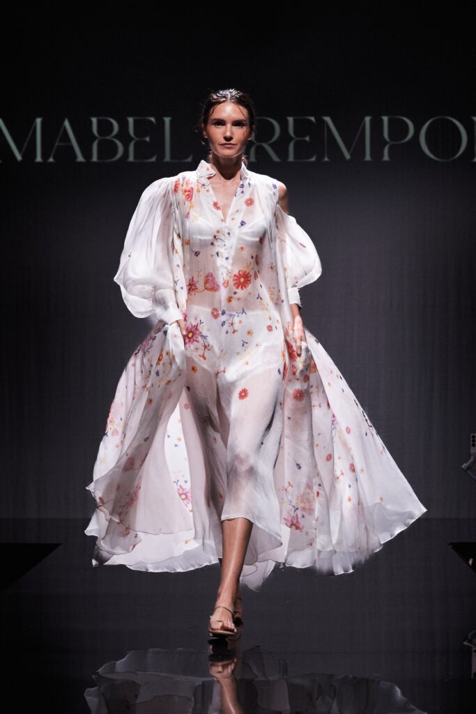 Model wearing a flowing white floral ensemble on the runway at Brisbane Fashion Month.