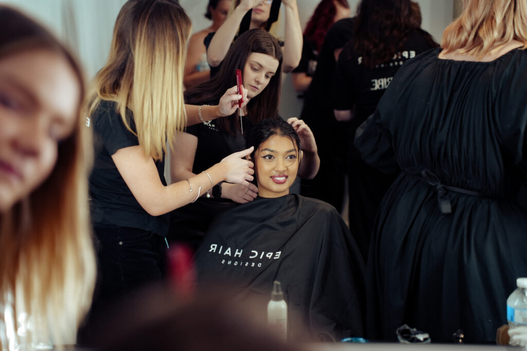 Epic Hair Designs stylists prepare a smiling model’s hair backstage at Brisbane Fashion Month.