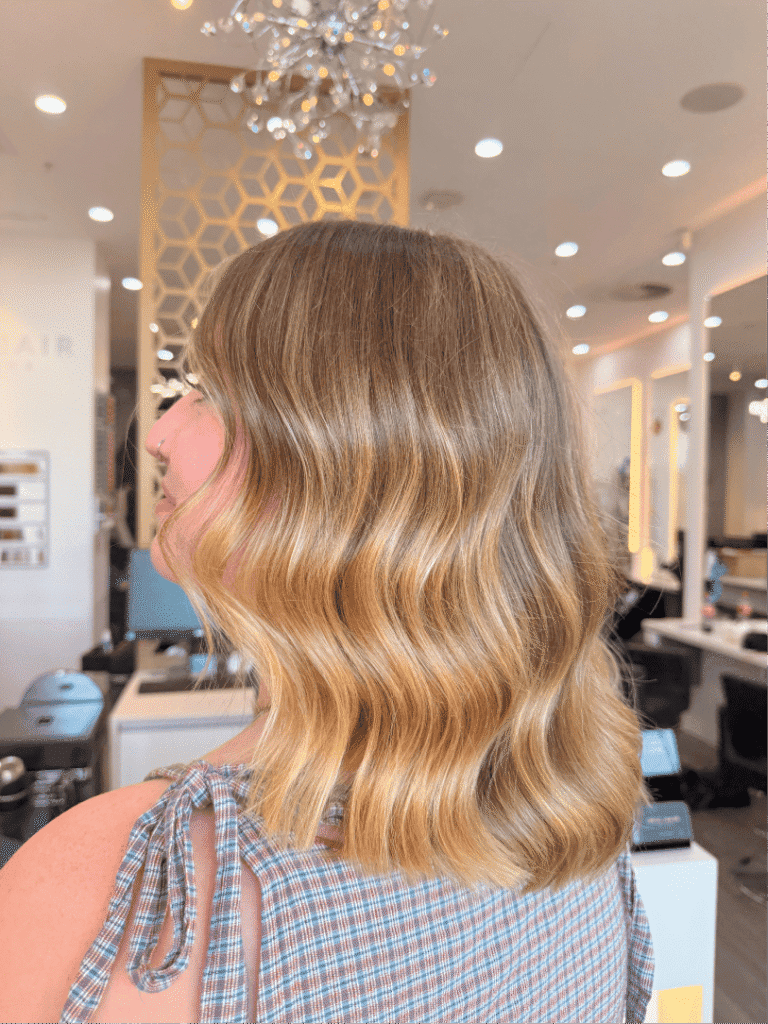 Warm Brontë Blonde balayage with natural roots and buttery-blonde mid-lengths and ends